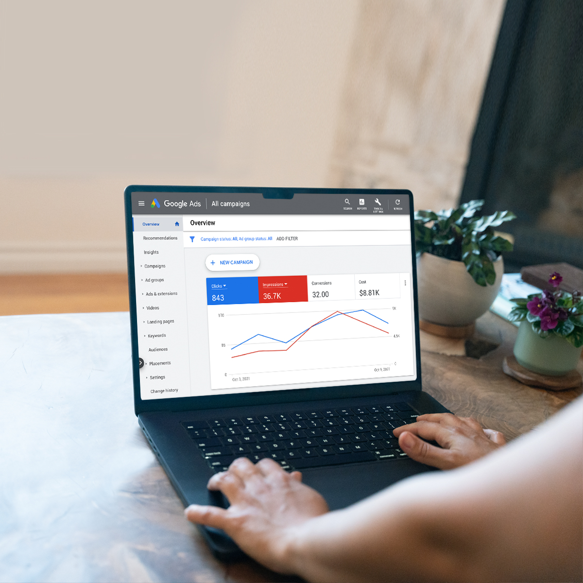 Close-up of hands using a laptop with SEM analytics dashboard showing graphs and performance metrics.