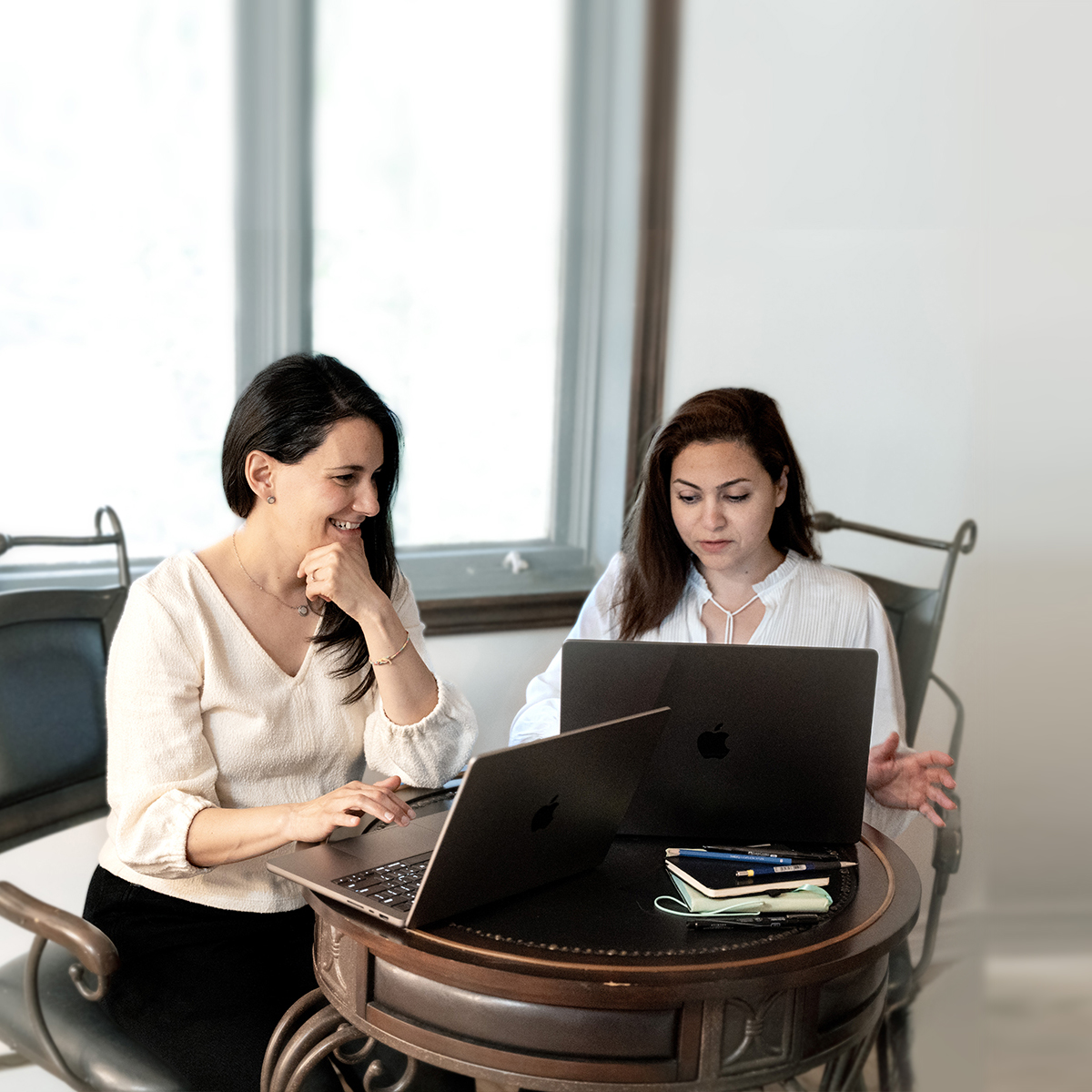 Two professionals collaborating on laptops, planning email marketing campaigns