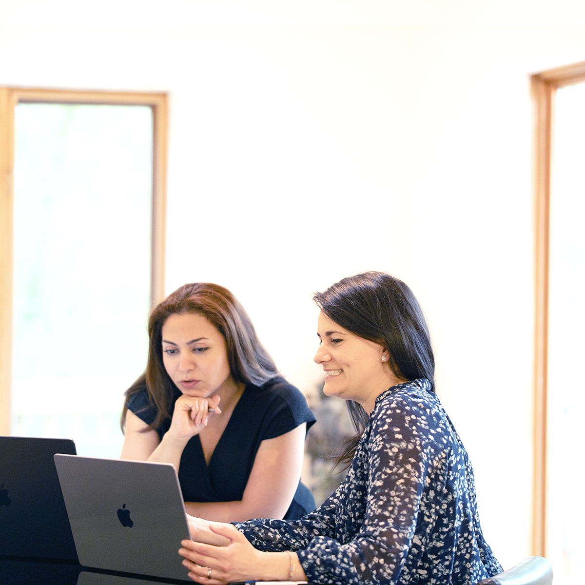 Two marketers collaborating on a laptop to plan SEM campaigns in a bright office setting